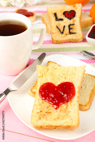 Delicious toast with jam and cup of tea on table close-up