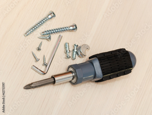 worn household tool. screwdriver and screw on wood backgrounds