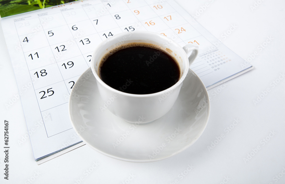 cup of coffee with wall calendar on white cup of coffee with wall calendar on white