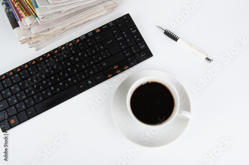 stack of newspapers and keyboard with cup of coffee close-up