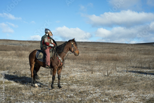 Ancient horseman in metal helmet observing steppe