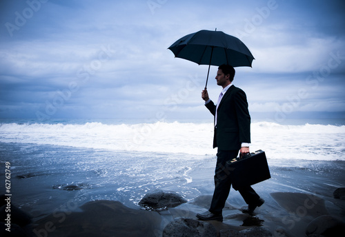 Businessman With Umbrella At Stormy Ocean