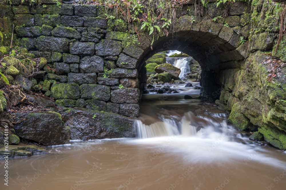 stone bridge over fast moving woodland stream stone bridge over fast moving woodland stream