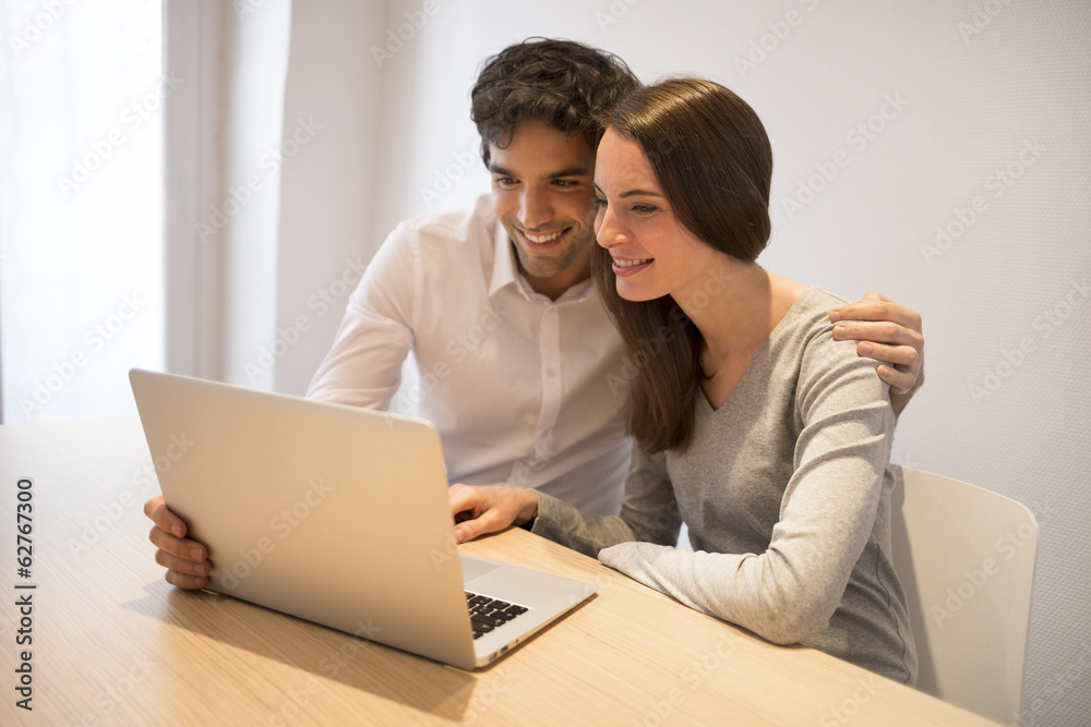 Cheerful couple surfing the net and Using Laptop At Home Cheerful couple surfing the net and Using Laptop At Home