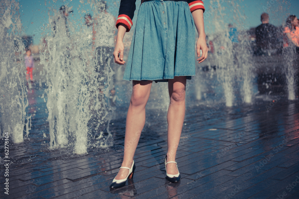 Young woman standing by fountain in city on a hot day Young woman standing by fountain in city on a hot day