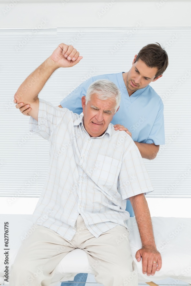 Obraz premium Mhysiotherapist assisting senior man to raise hand