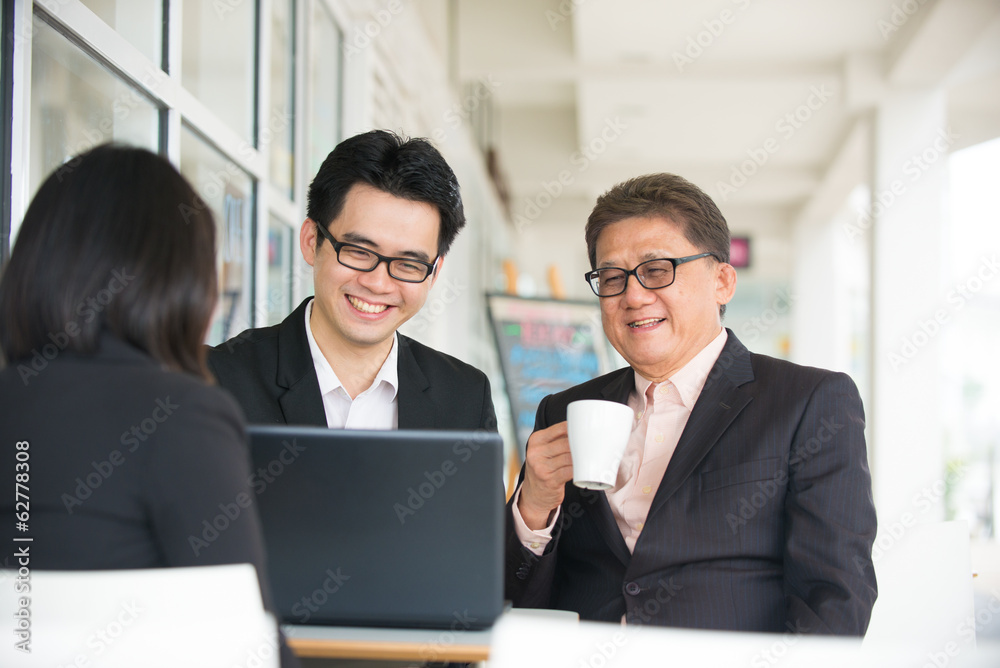 Group of asian business people gathered together at a table dis Group of asian business people gathered together at a table dis