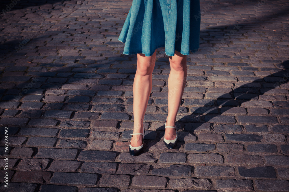 Young woman in skirt walking on a cobbled street Young woman in skirt walking on a cobbled street