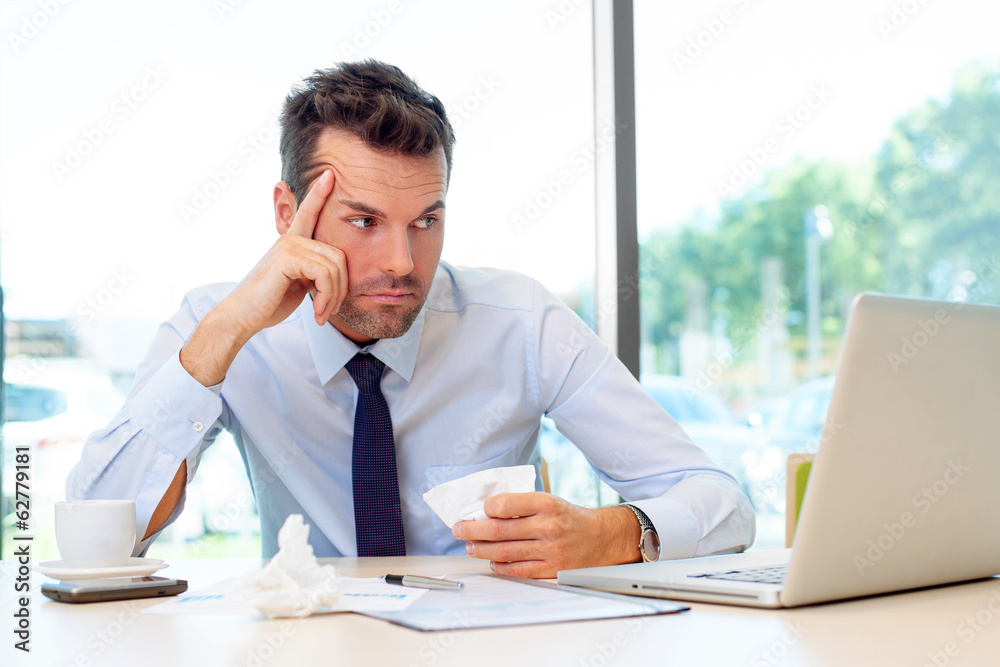 Sick man working on laptop in the office Sick man working on laptop in the office