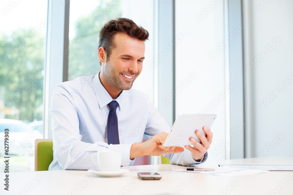Happy businessman browsing web on digital tablet