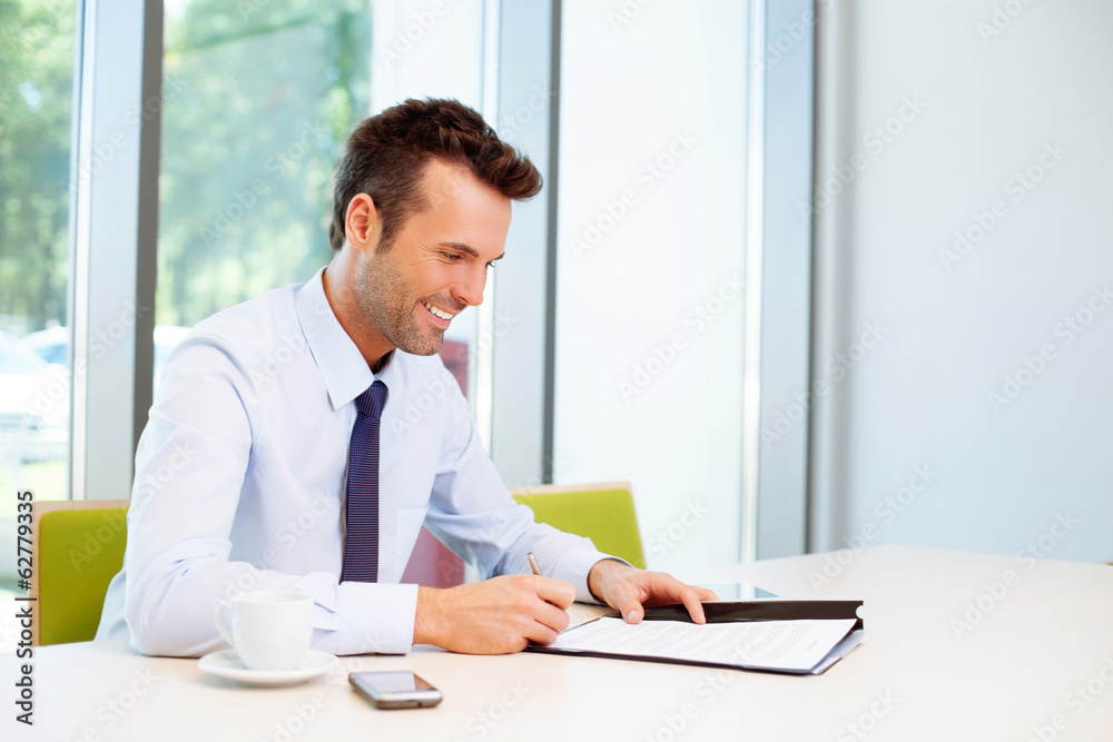 Happy man signing document in the office Happy man signing document in the office