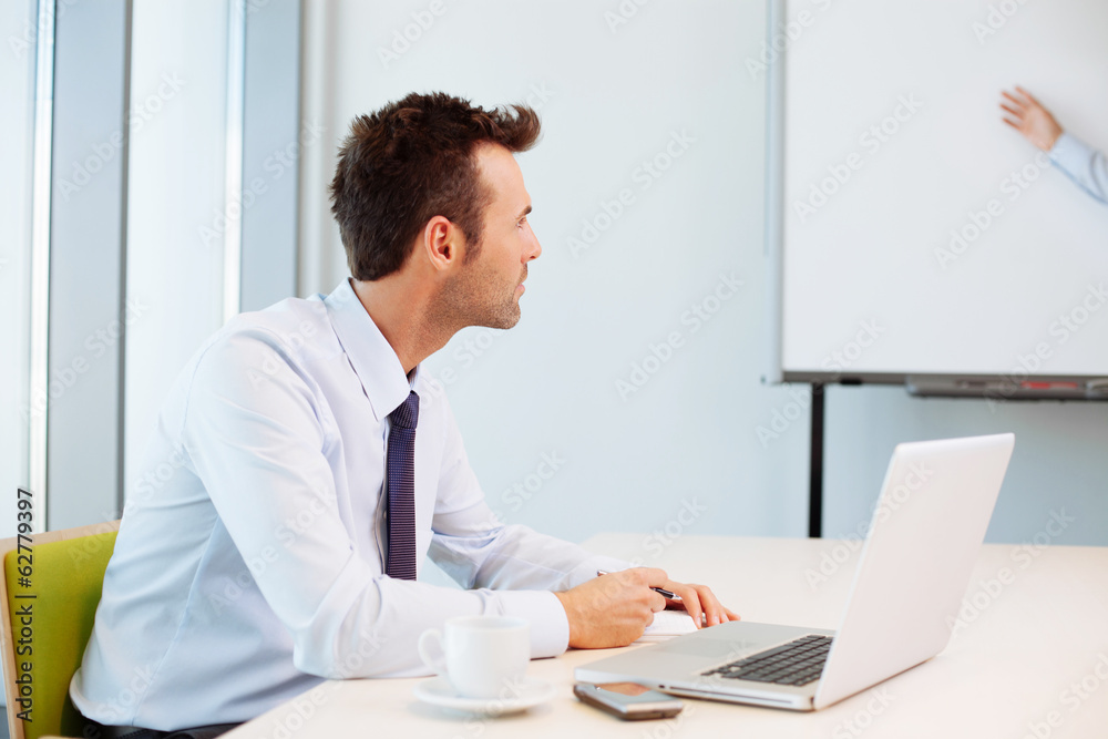 Businessman writing notes during business meeting