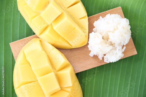 Ripe mango and sticky rice in bamboo dish on banana leaves. photo