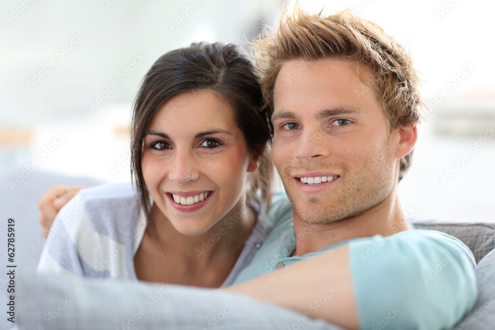 Smiling young couple relaxing in sofa at home Smiling young couple relaxing in sofa at home