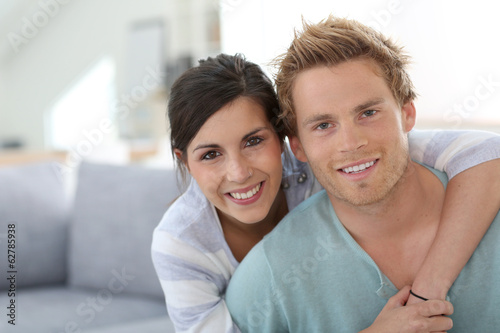 Smiling young couple relaxing in sofa at home © goodluz
