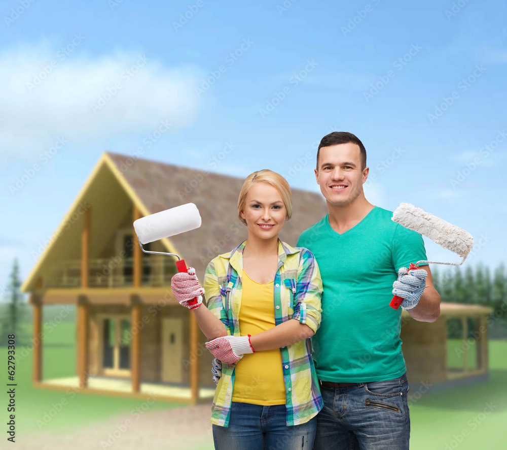 smiling couple in gloves with paint rollers