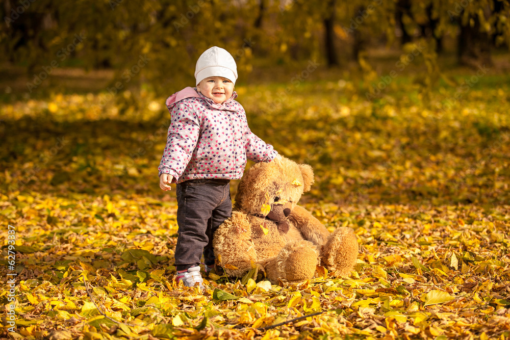 Small girl in pink coat holding big teddy bear at autumn park Small girl in pink coat holding big teddy bear at autumn park