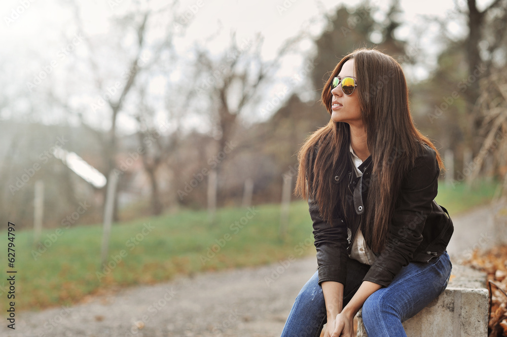 Attractive modern woman sitting in a autumn park Attractive modern woman sitting in a autumn park