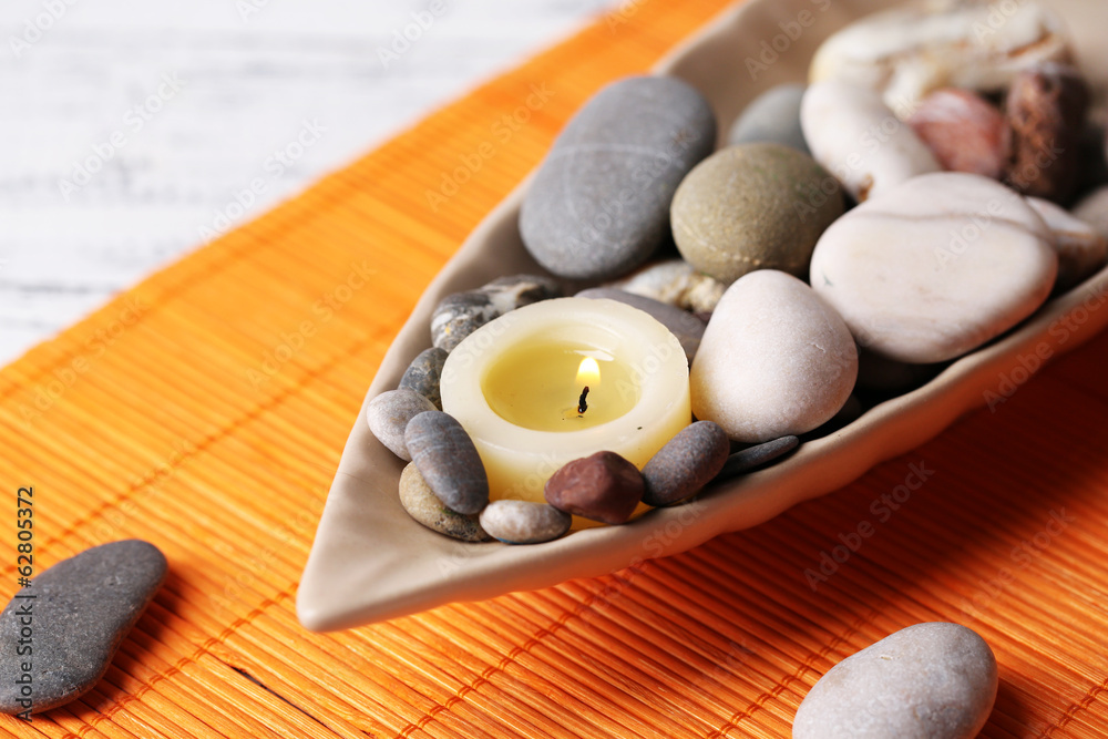 Composition with spa stones, candles on bamboo mat background
