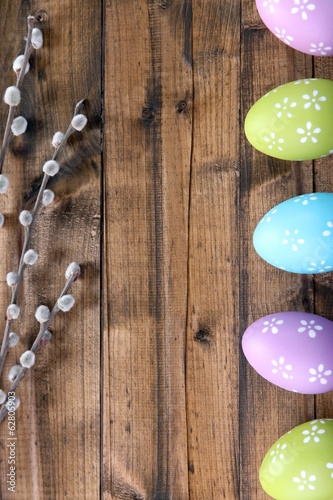 Easter eggs and pussy-willow bud on wooden background