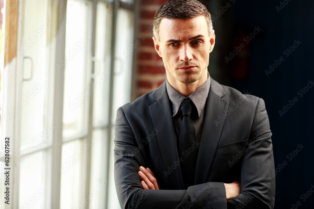 Thoughtful businessman standing with arms folded Thoughtful businessman standing with arms folded
