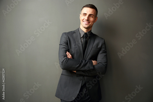 Cheerful businessman with arms folded standing 