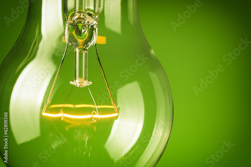 Close up glowing light bulb on green background photo