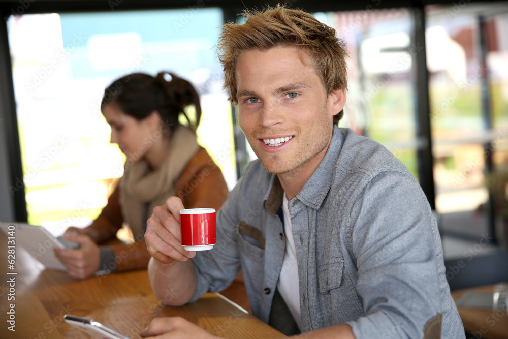 Young man in coffee shop wonnected on smartphone Young man in coffee shop wonnected on smartphone