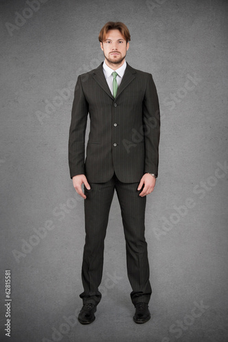 Young businessman full body front portrait against grunge backgr