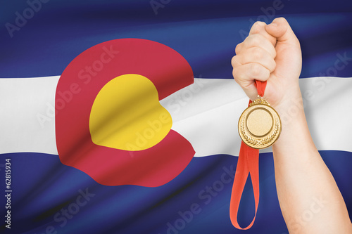 Medal in hand with flag on background - State of Colorado. photo