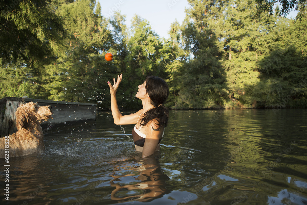 A woman swimming with her two dogs in a lake. Throwing the ball in play. A woman swimming with her two dogs in a lake. Throwing the ball in play.