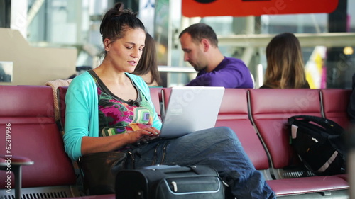 Young woman finish working on laptop while waiting on the airpor photo