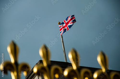 Obraz na plátně golden fence of buckingham palace with british flag