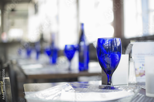 A cafe interior. Bright blue glassware on empty tables.