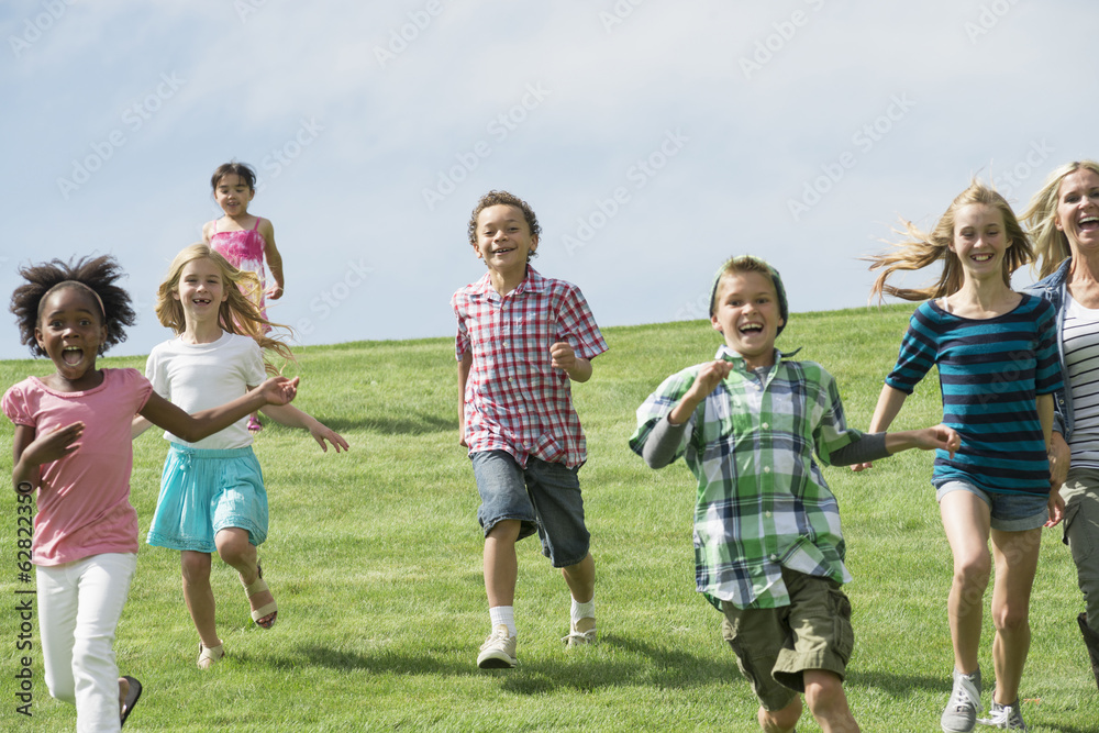 A group of children running across a grass field. A group of children running across a grass field.