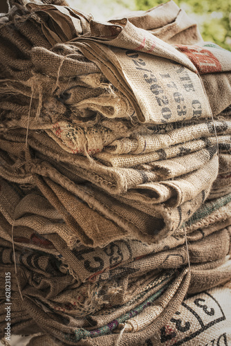 A pile of empty stamped hessian sacks bundled up for reuse or recycling, in a coffee processing plant. 