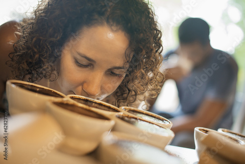 A woman sampling in a coffee processing shed, where staff make coffee in small pots and sample the taste to test the blend. 