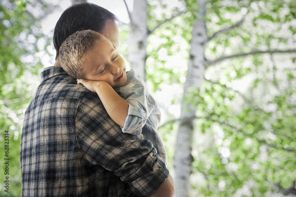A man cradling a sleeping child, resting on his shoulder. A man cradling a sleeping child, resting on his shoulder.