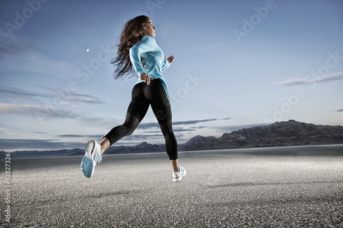 A young woman running through the landscape on the salt flats surface near Salt Lake city. 