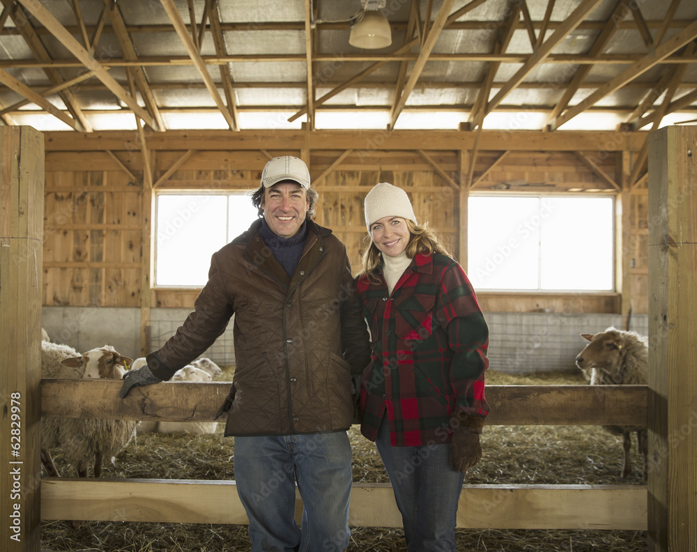 An Organic Farm in Winter in Cold Spring, New York State. A farmer and a woman standing by a pen full of sheep. An Organic Farm in Winter in Cold Spring, New York State. A farmer and a woman standing by a pen full of sheep.