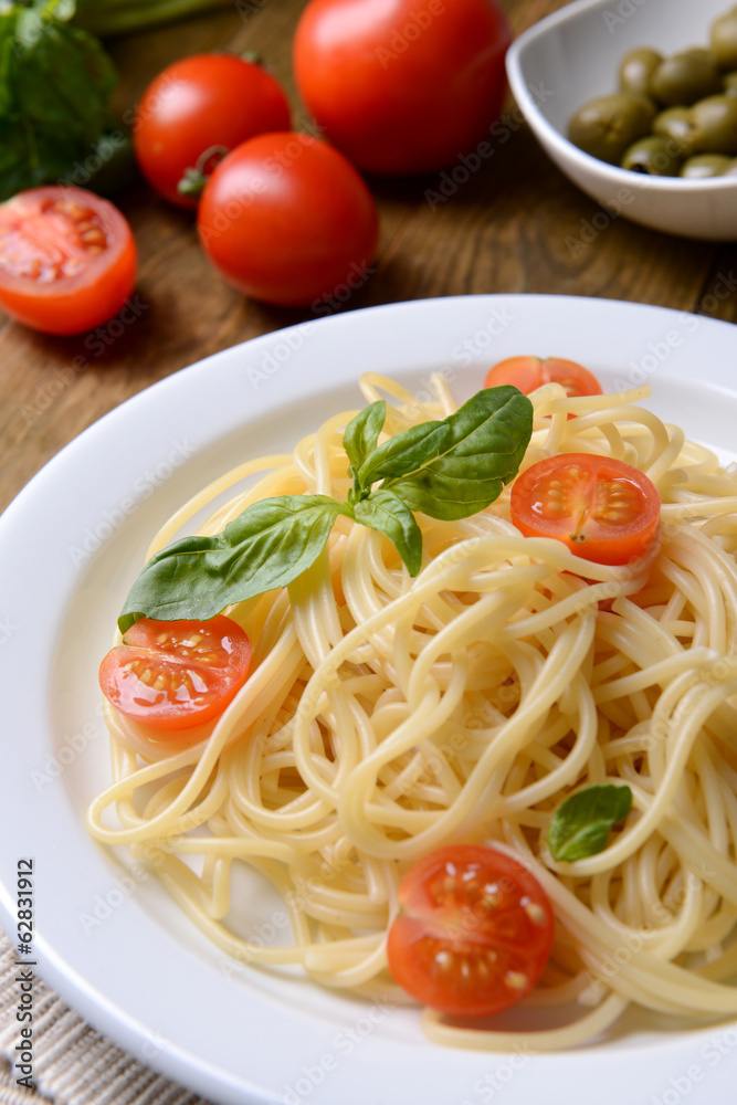 Delicious spaghetti with tomatoes on plate on table close-up Delicious spaghetti with tomatoes on plate on table close-up