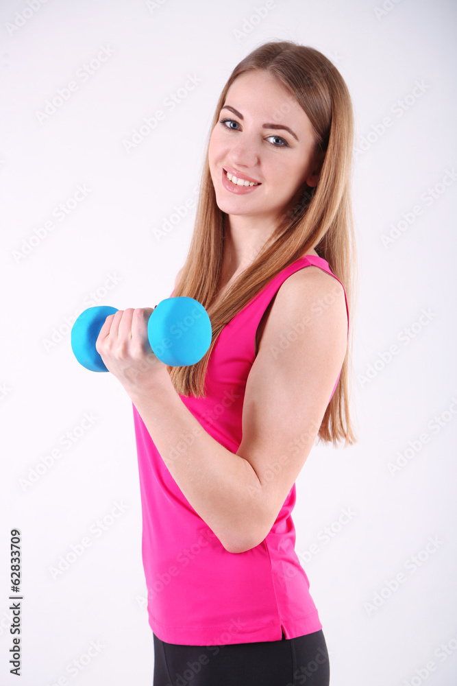 Young beautiful fitness girl exercising with dumbbells in gym Young beautiful fitness girl exercising with dumbbells in gym