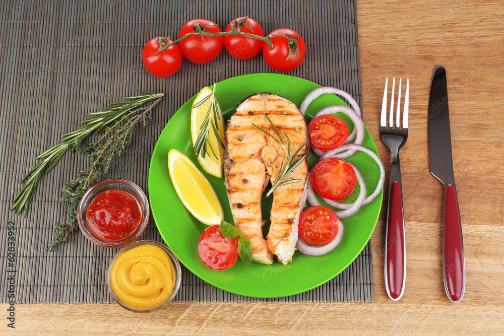 Tasty grilled salmon with vegetables, on wooden table Tasty grilled salmon with vegetables, on wooden table