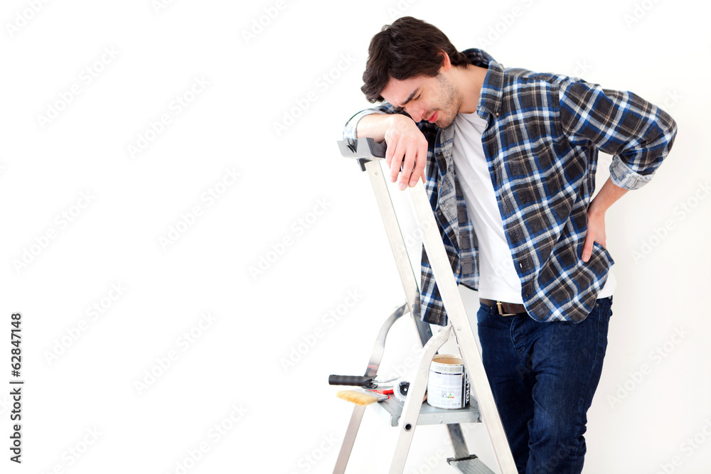 Young man suffering while working on a stepladder