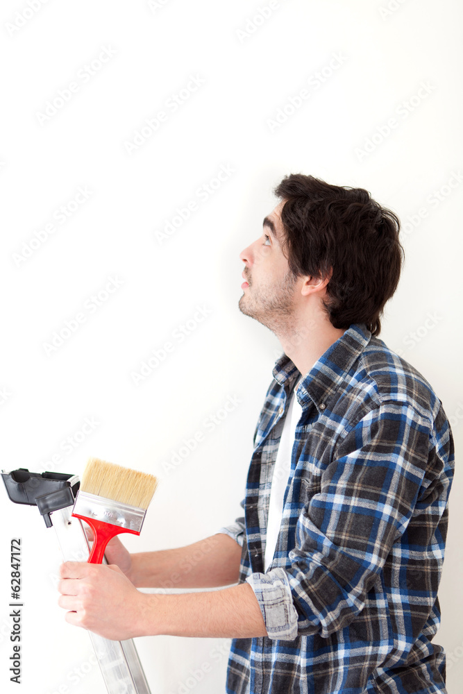 Attractive young man painting a wall in his new flat Attractive young man painting a wall in his new flat