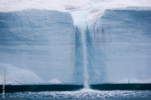 A waterfall is created by a melting iceberg, Svalbard, Norway photo