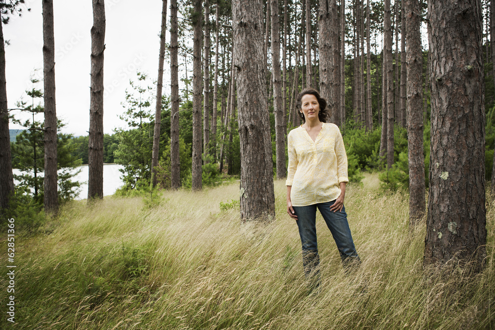 A woman in open countryside, by a mountain lake. 