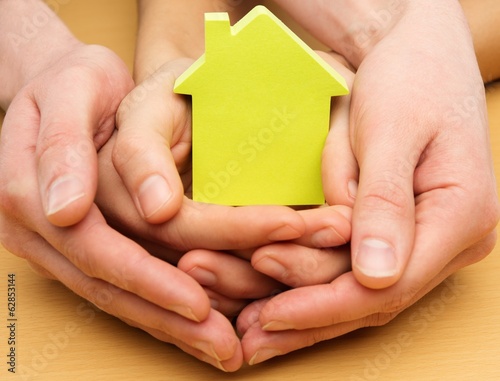 Man and woman hands holding conceptual paper house