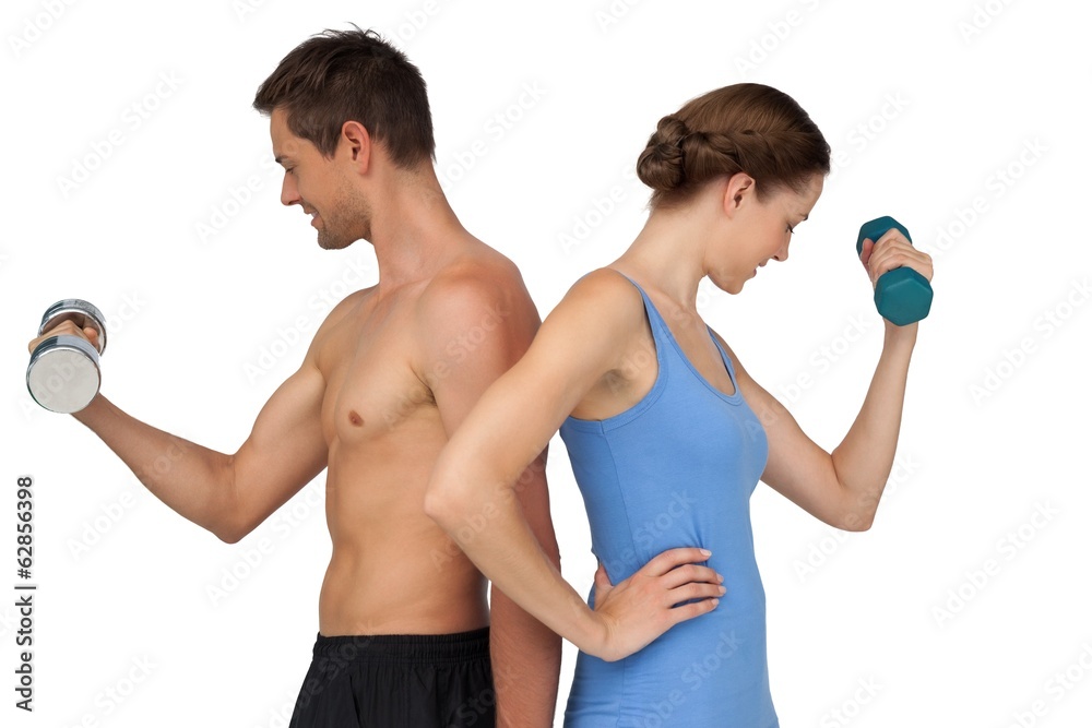 Fit young couple exercising with dumbbells Fit young couple exercising with dumbbells