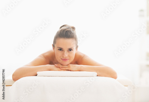 Happy young woman laying on massage table